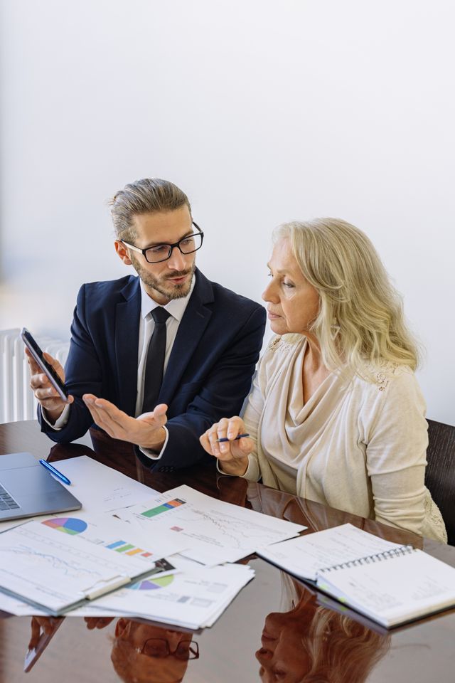 Conseiller en costume présentant des graphiques à une cliente blonde lors d'un rendez-vous de bureau