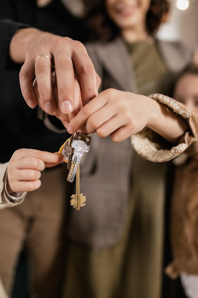 Mains d'un adulte remettant un trousseau de clés à un enfant entouré de sa famille