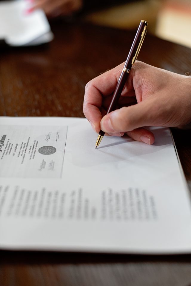 Main tenant un stylo plume et signant un document officiel portant un sceau imprimé