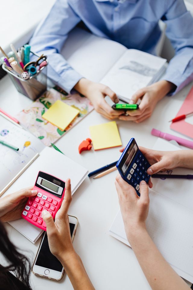Mains de plusieurs personnes utilisant des calculatrices autour d'une table couverte de post-it