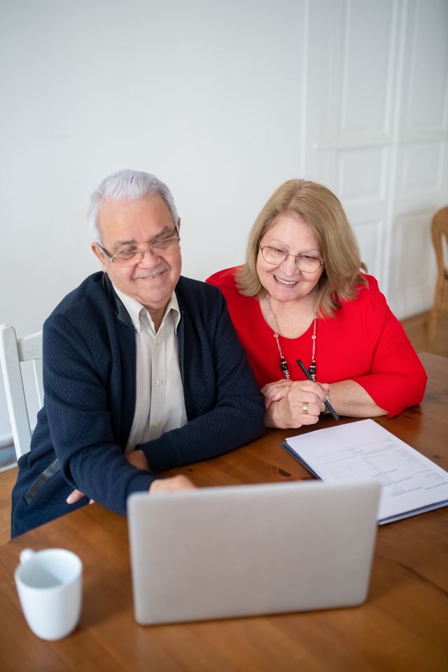 Couple de seniors souriants consultant un ordinateur portable à une table de cuisine