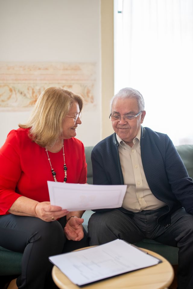 Couple de seniors assis lisant ensemble des documents imprimés près d'une table basse