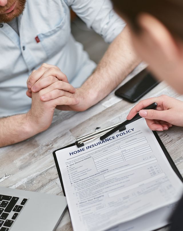 Porte-bloc avec un formulaire d'assurance habitation tendu à un client, mains jointes