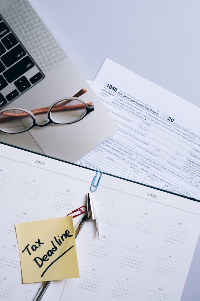 Formulaire fiscal, lunettes, calendrier et post-it Tax deadline près d'un ordinateur portable