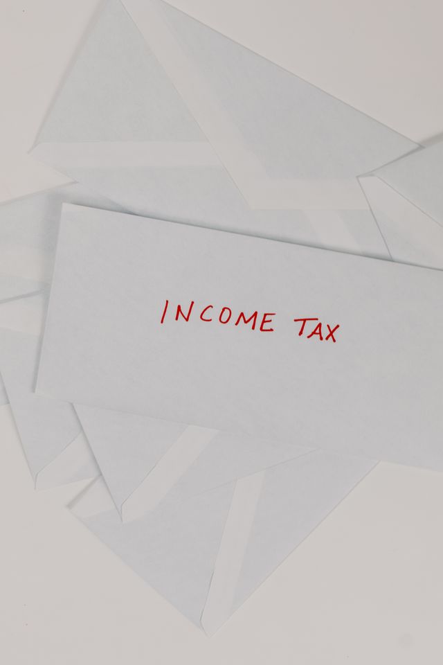 Enveloppe blanche portant l'inscription Income tax en lettres rouges parmi d'autres enveloppes