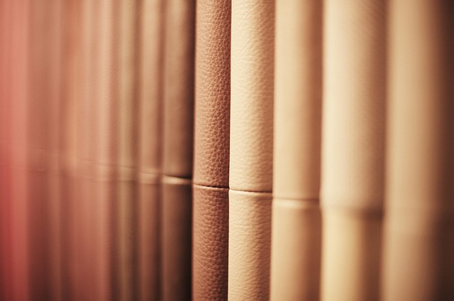 Gros plan flou sur des dos de livres reliés en cuir aux tons rosés et dorés alignés sur une étagère