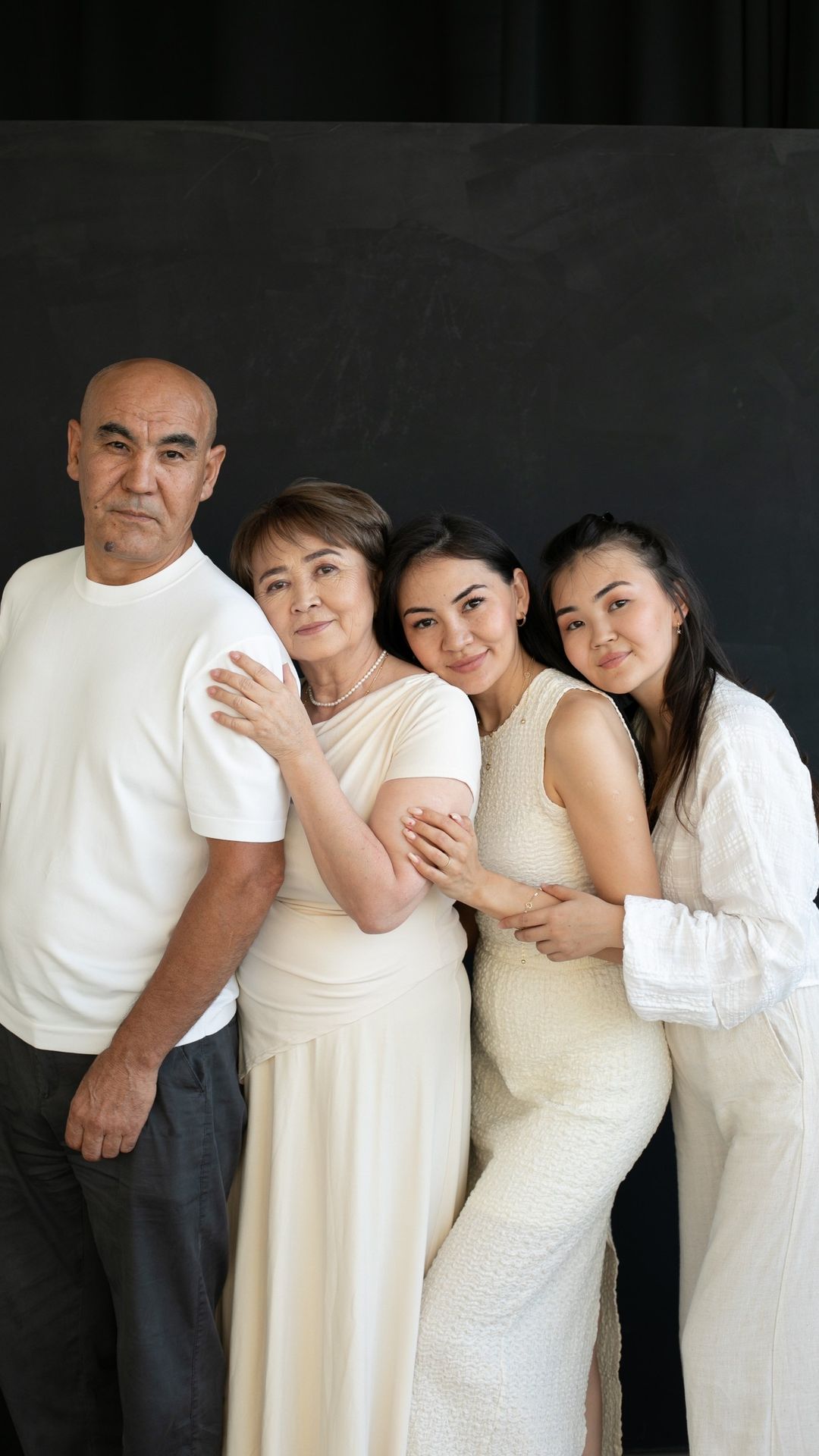 Portrait de quatre membres d'une famille d'âges différents, vêtus de blanc, serrés les uns contre les autres