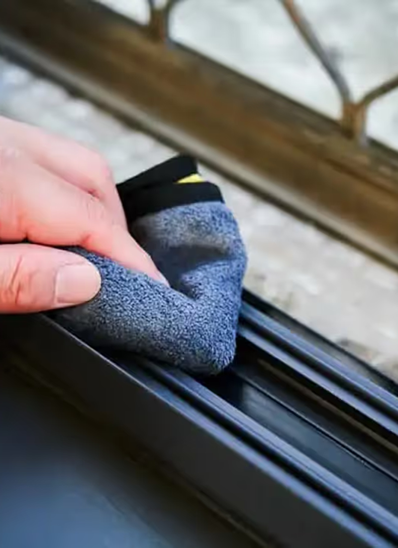 Hand detailing a window sill and track with a cloth