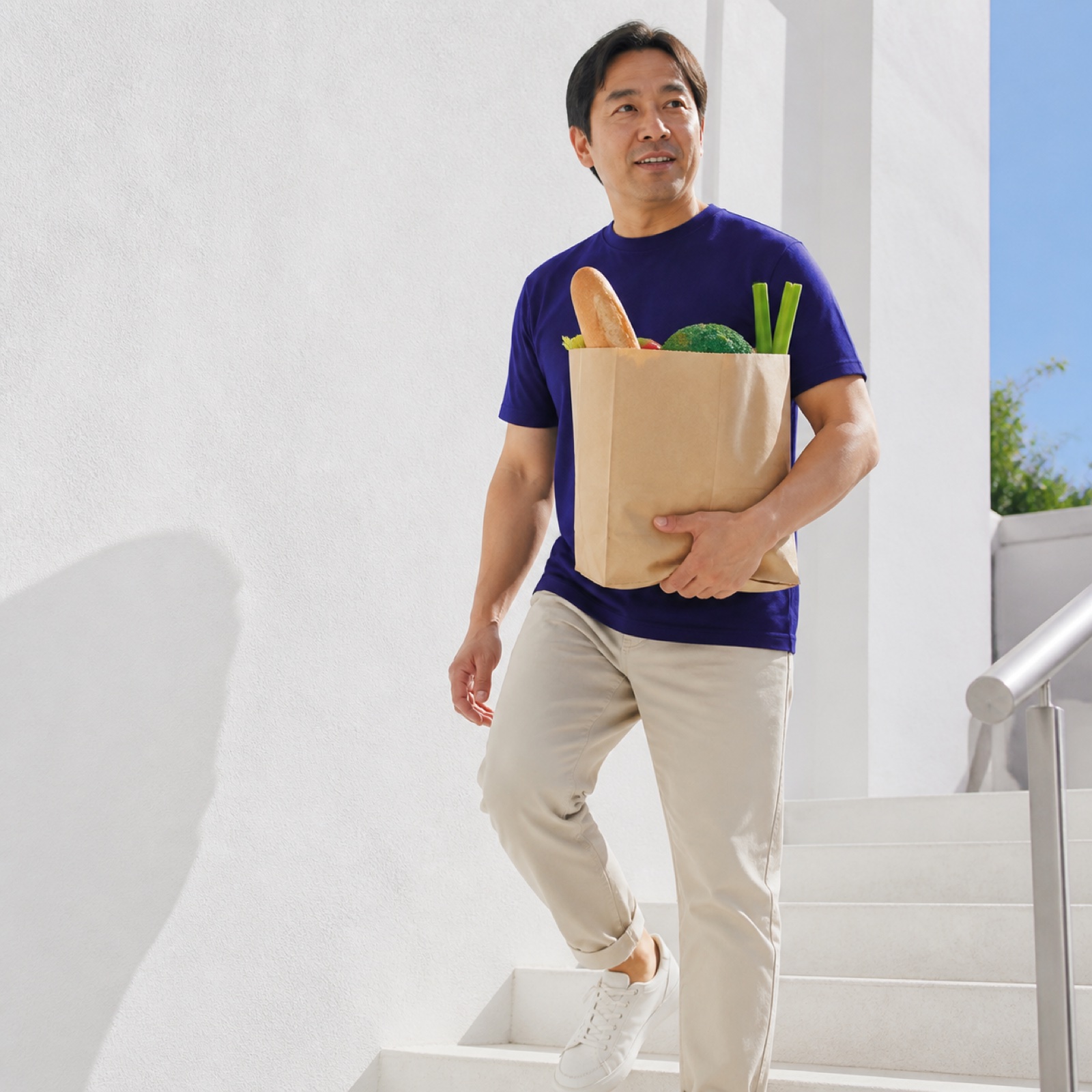 Man carrying groceries up bright outdoor steps