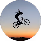 Silhouette eines Fahrradfahrers, der bei Sonnenuntergang einen Sprung ausführt.