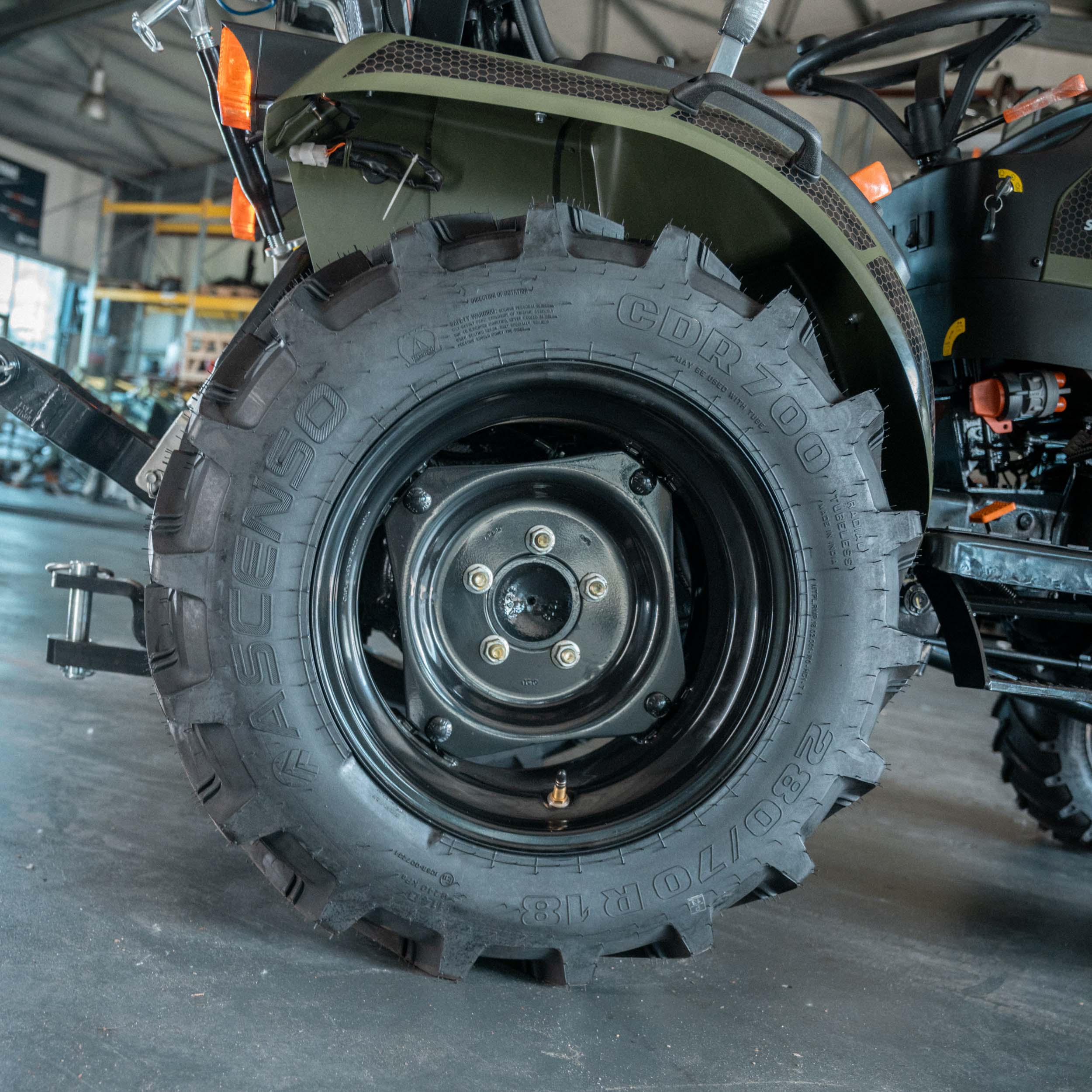 Nahaufnahme eines grobstolligen Reifen eines landwirtschaftlichen Fahrzeugs in einer Werkstatt.