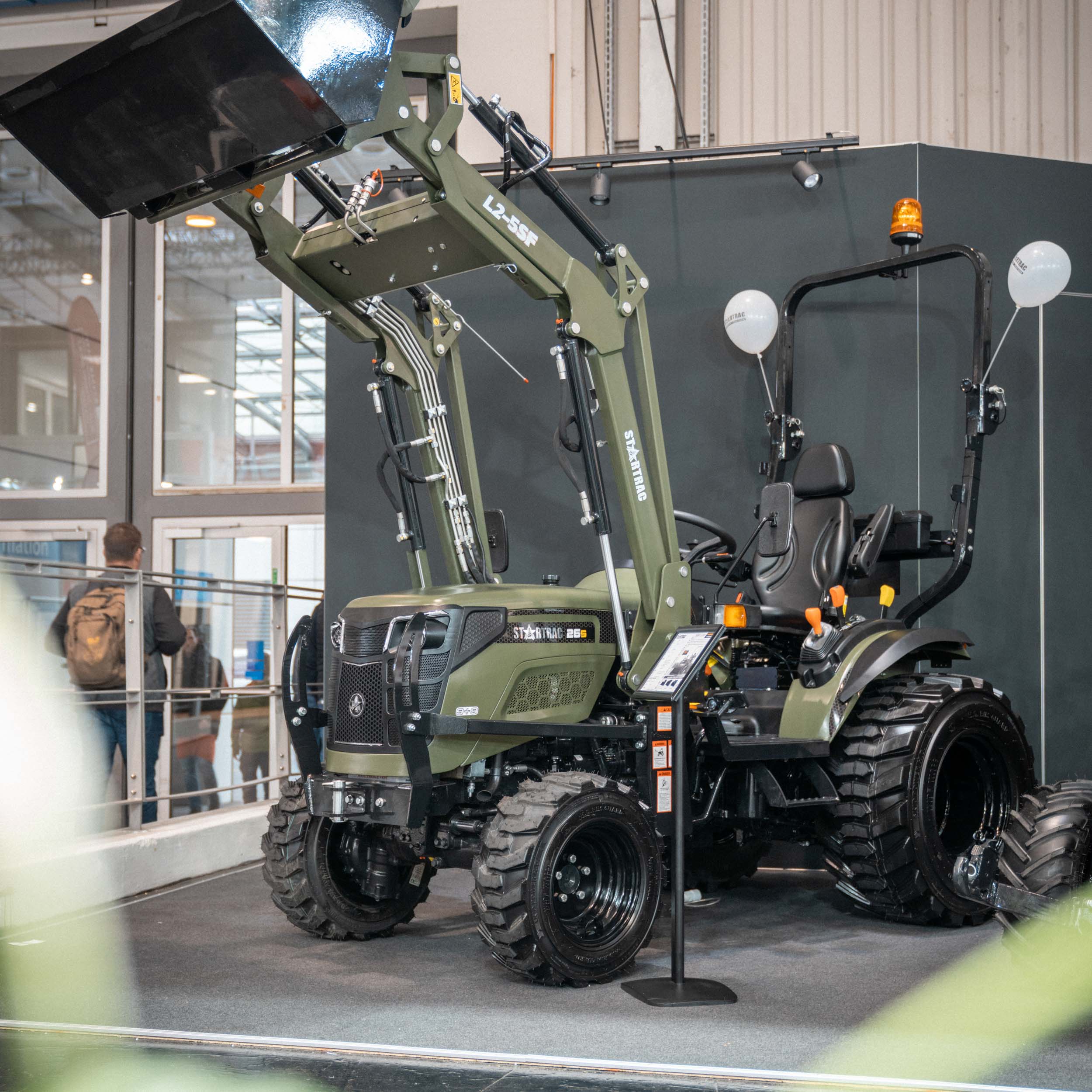 Grüner Startrac 265 Traktor mit Frontlader in einer Innenausstellung.