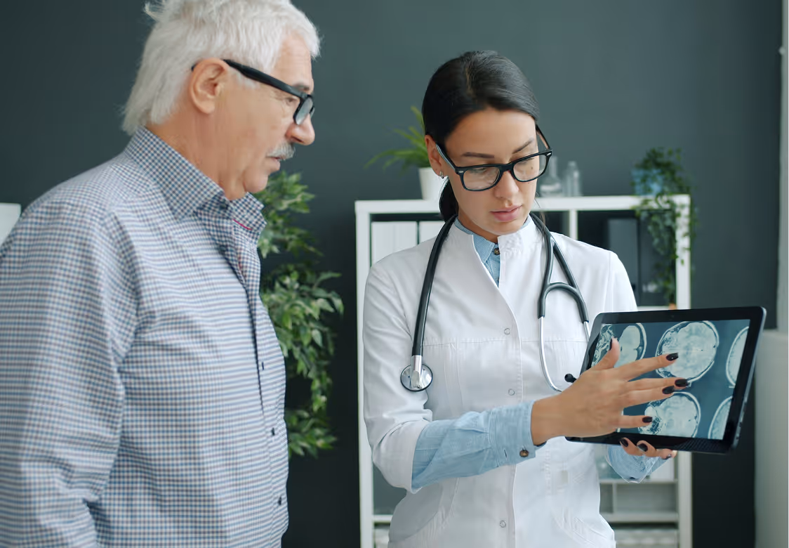 A doctor showing her senior male patient digital MRI scans on her tablet device