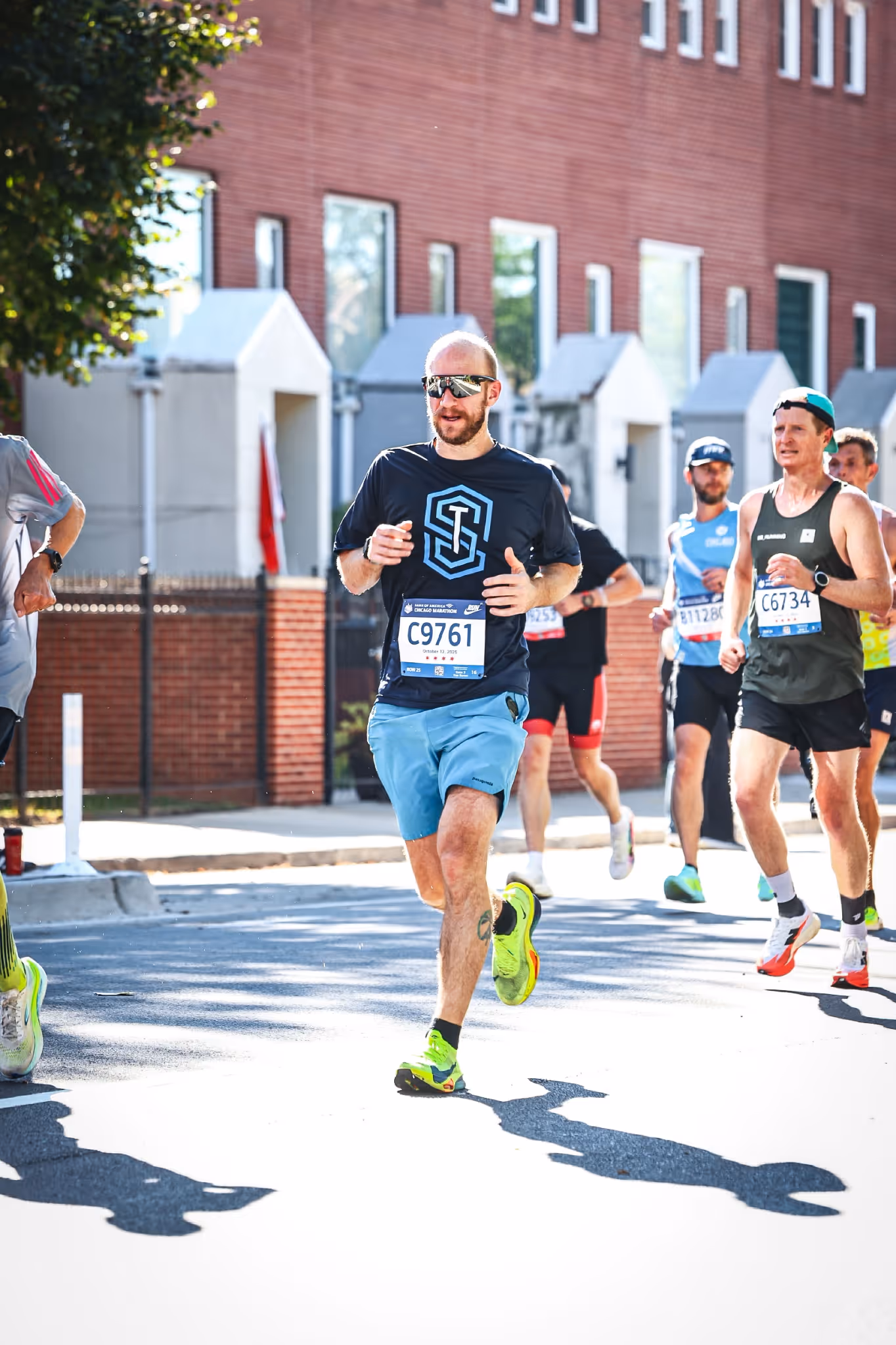 Group of runners participating in a marathon on a city street with brick buildings in the background.
