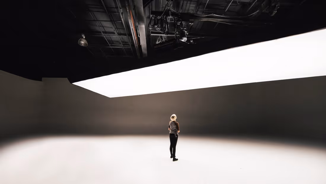 Person standing in a large white cyc wall sound stage at Thunder Studios with overhead lighting grid