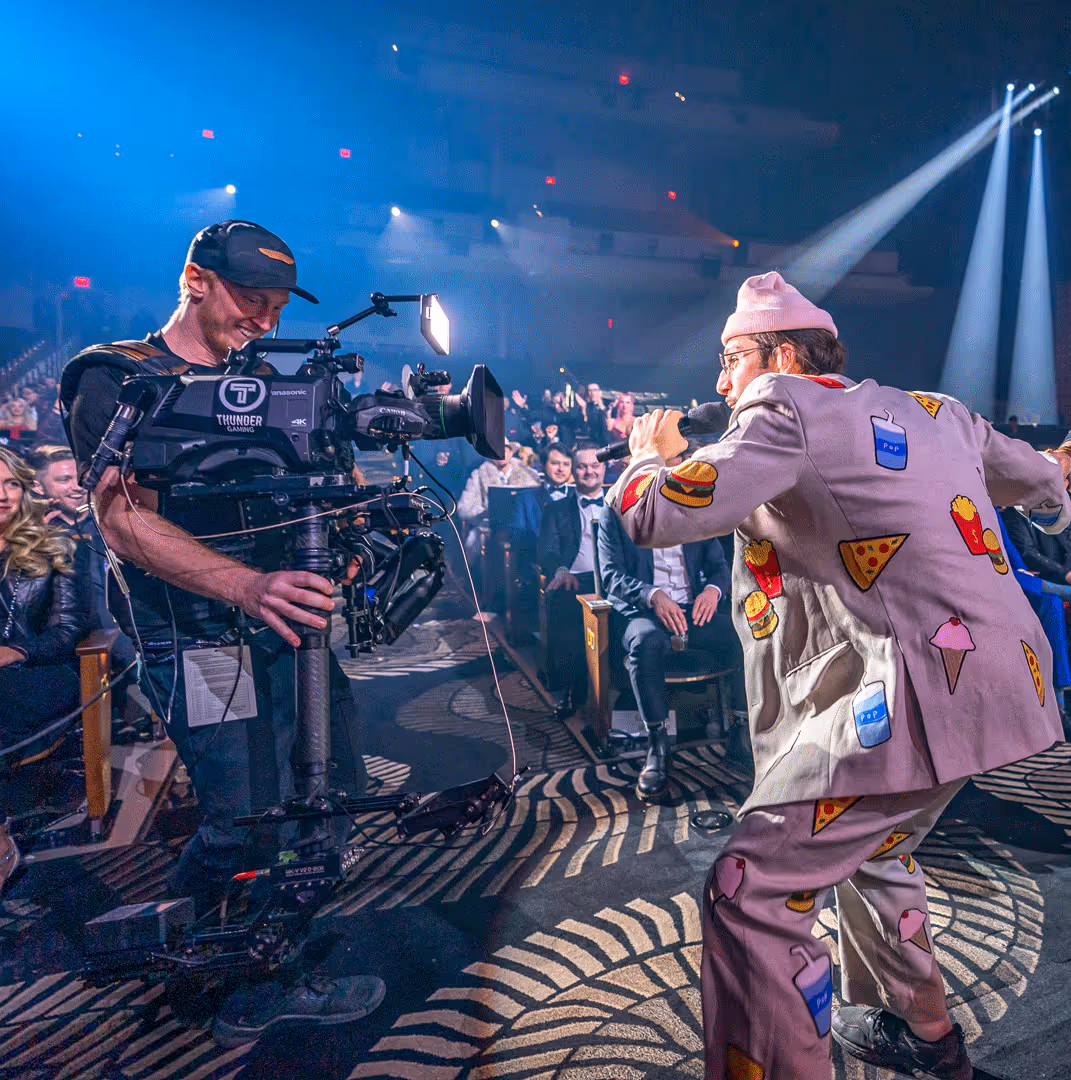 A Thunder Studios camera operator filming a performer in front of a seated live audience