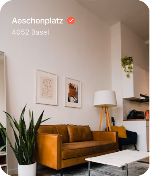 Modern living room with sofa, abstract artworks, floor lamp, a green plant in a white pot, and a white coffee table.