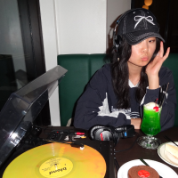 Portrait of Mandy Zhang in a record cafe, listening to music.