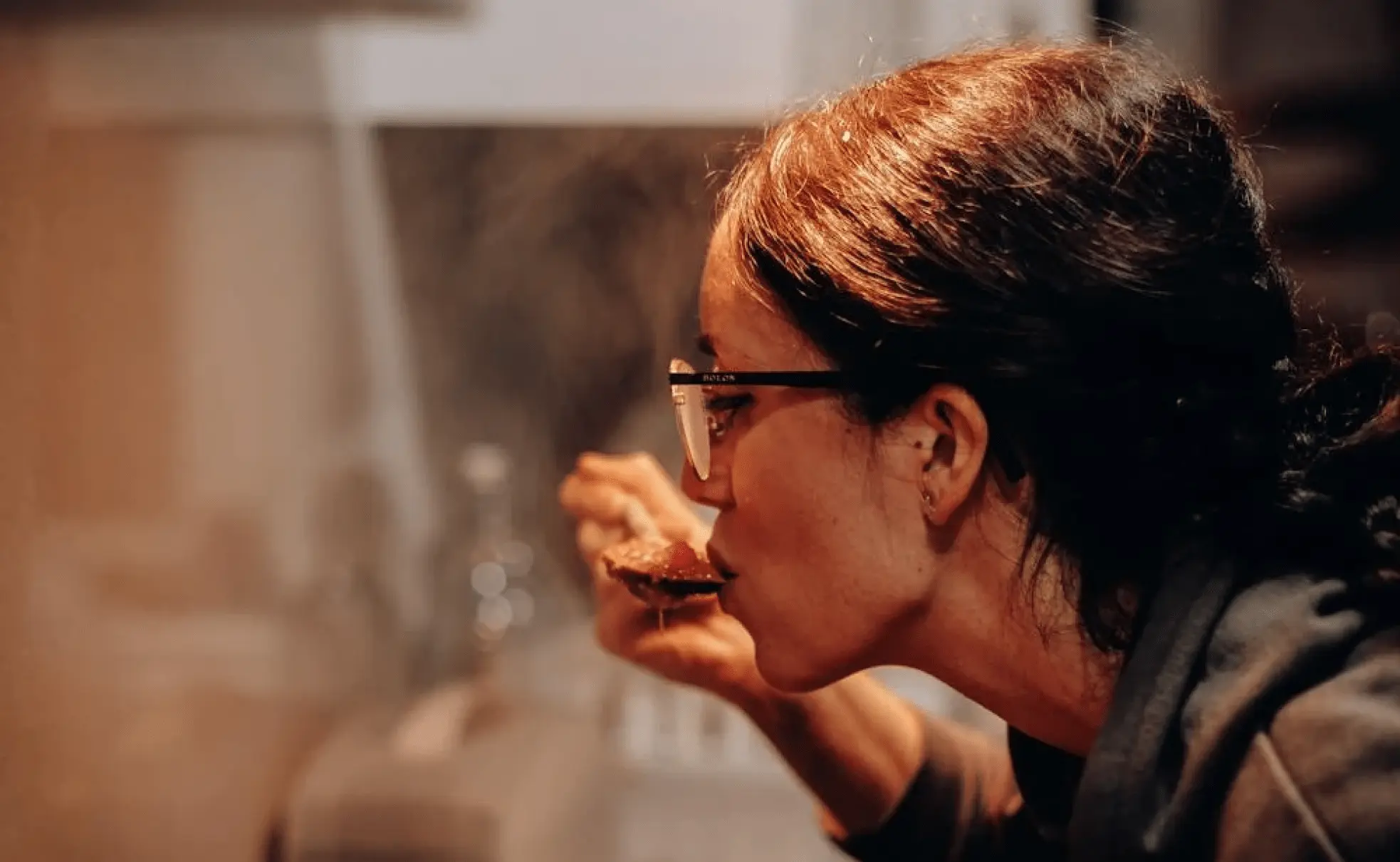 A young woman trying the food she is cooking