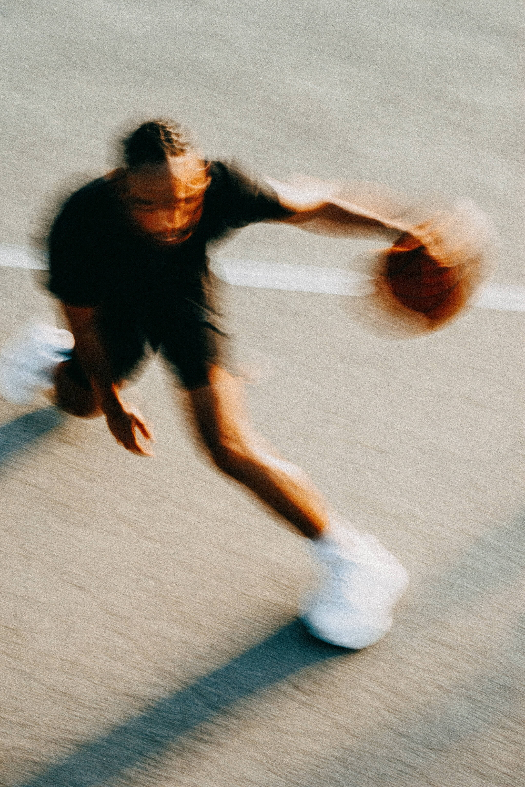 Blurred action shot of a basketball player dribbling on an outdoor court.