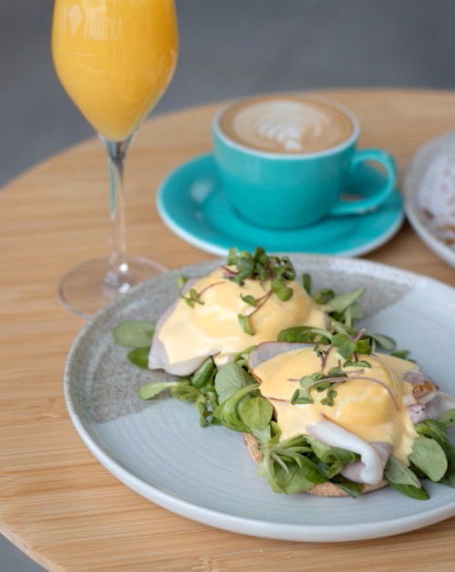 Vejce benedikt s holandskou omáčkou, kávou a mimózou na stole
