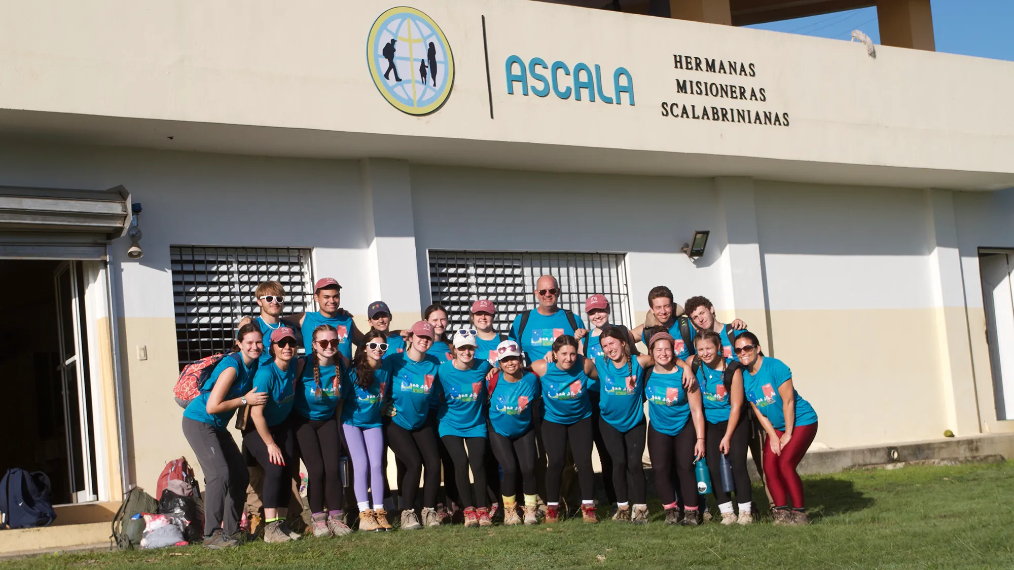 A group of students in matching blue shirts posing in front of a building in the Dominican Republic