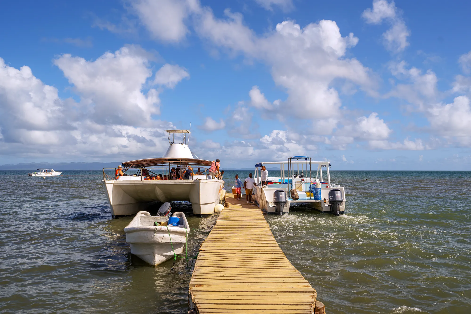 A catamaran carrying passengers over turquoise reef water in the Dominican Republic
