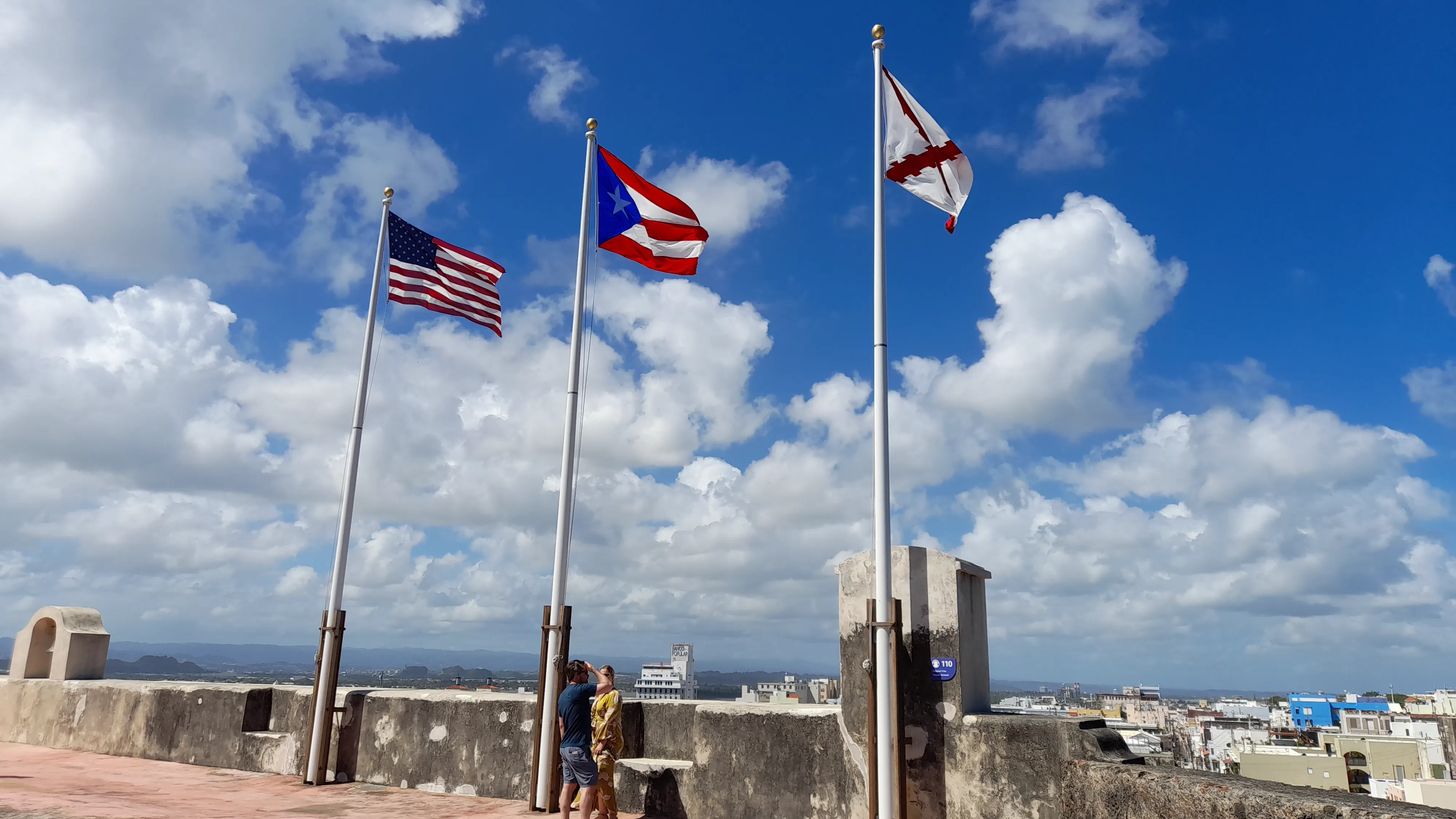 The U.S. and Puerto Rico flags flying against a blue, cloud-filled sky in Puerto Rico