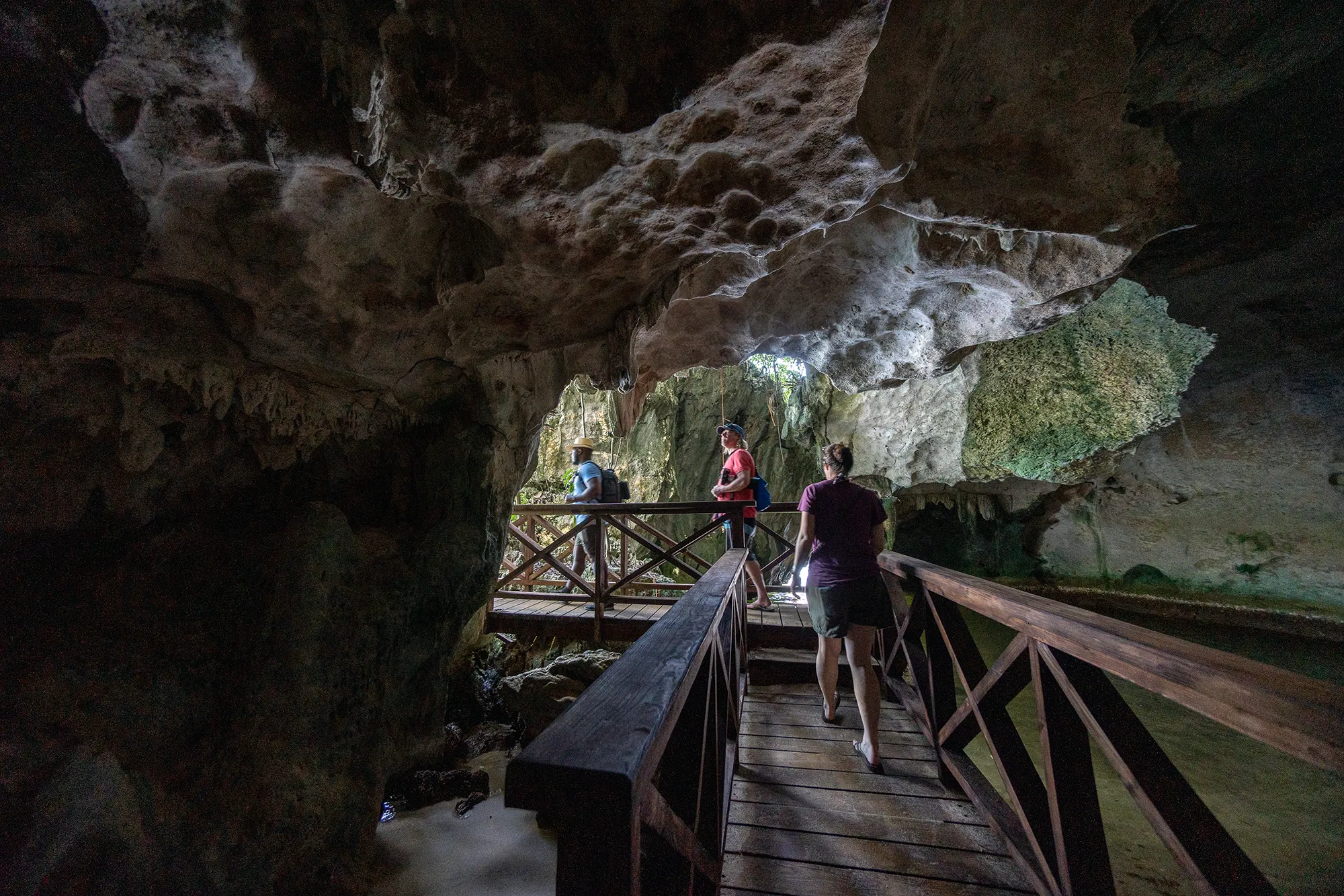 Travelers on a wooden walkway inside a coastal cave in Los Haitises National Park, Dominican Republic