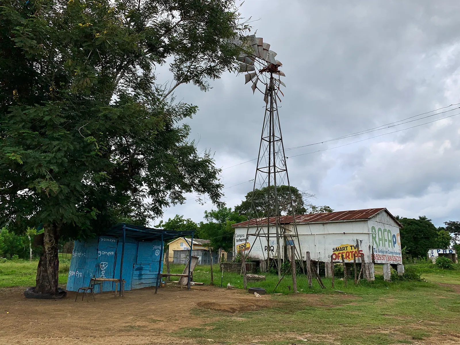 A rural Dominican Republic scene with a house and trees under a cloudy sky