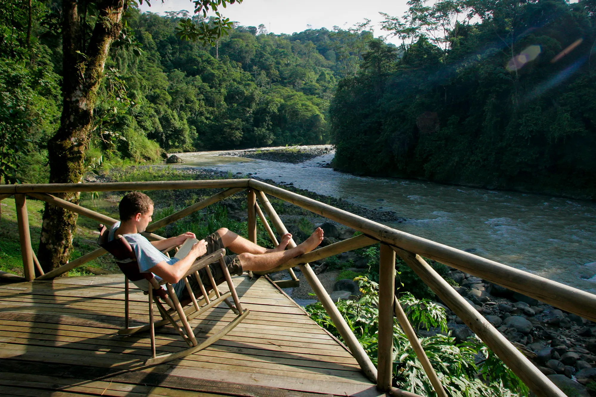 A traveler relaxing with feet up on a railing overlooking a river valley in Costa Rica