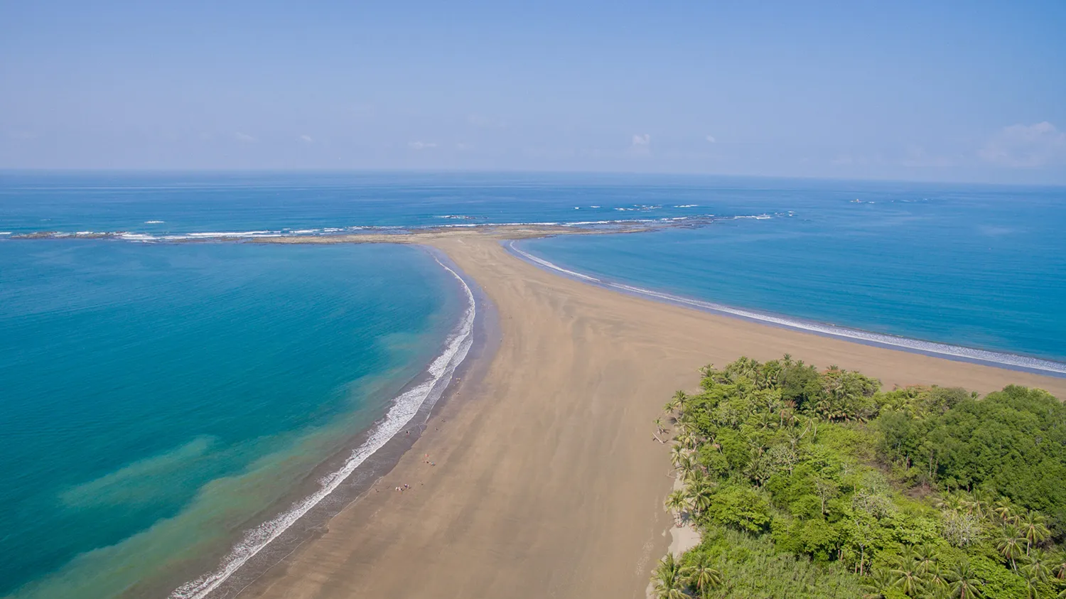 An aerial view of a curved sandy beach spit along the Costa Rica coast
