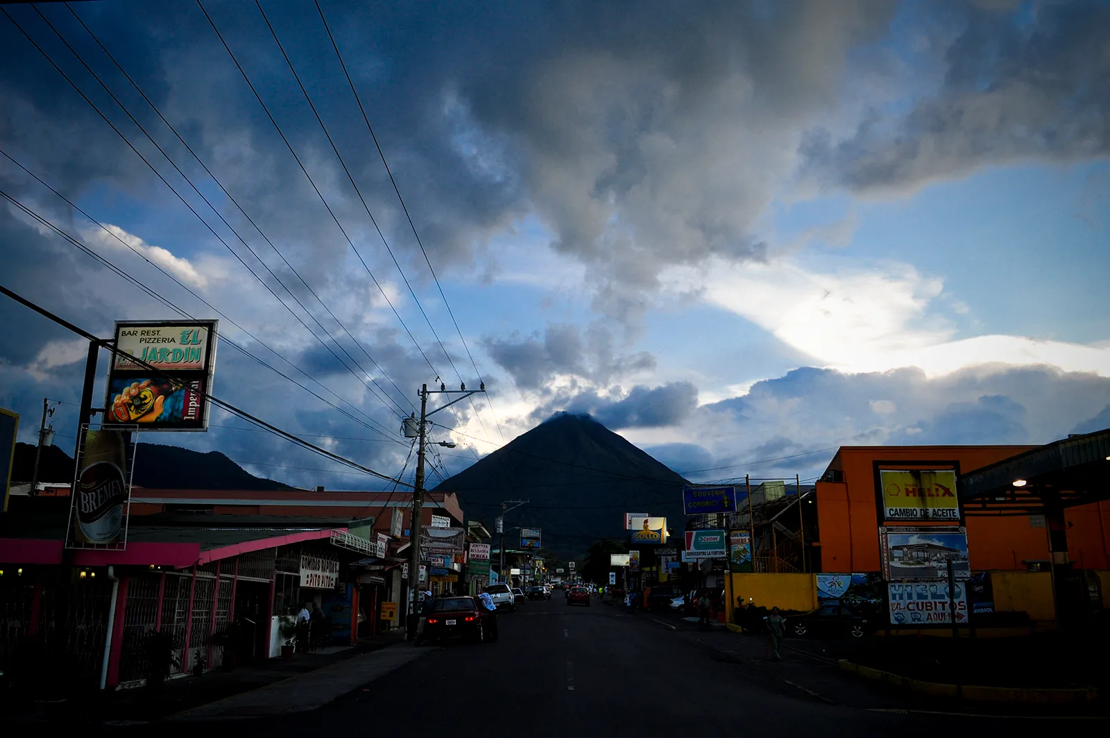 Arenal Volcano silhouetted at dusk beyond a small-town street in Costa Rica