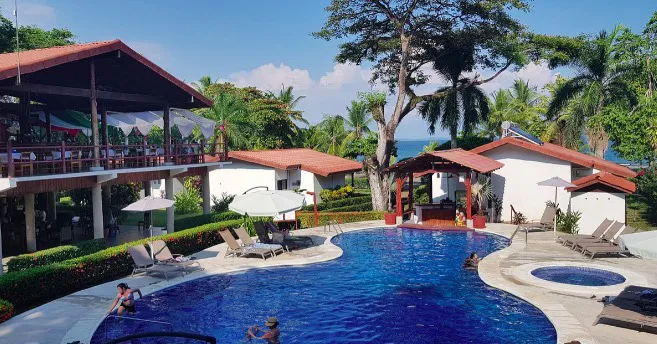 A rainforest lodge with a swimming pool and thatched-roof buildings in Costa Rica