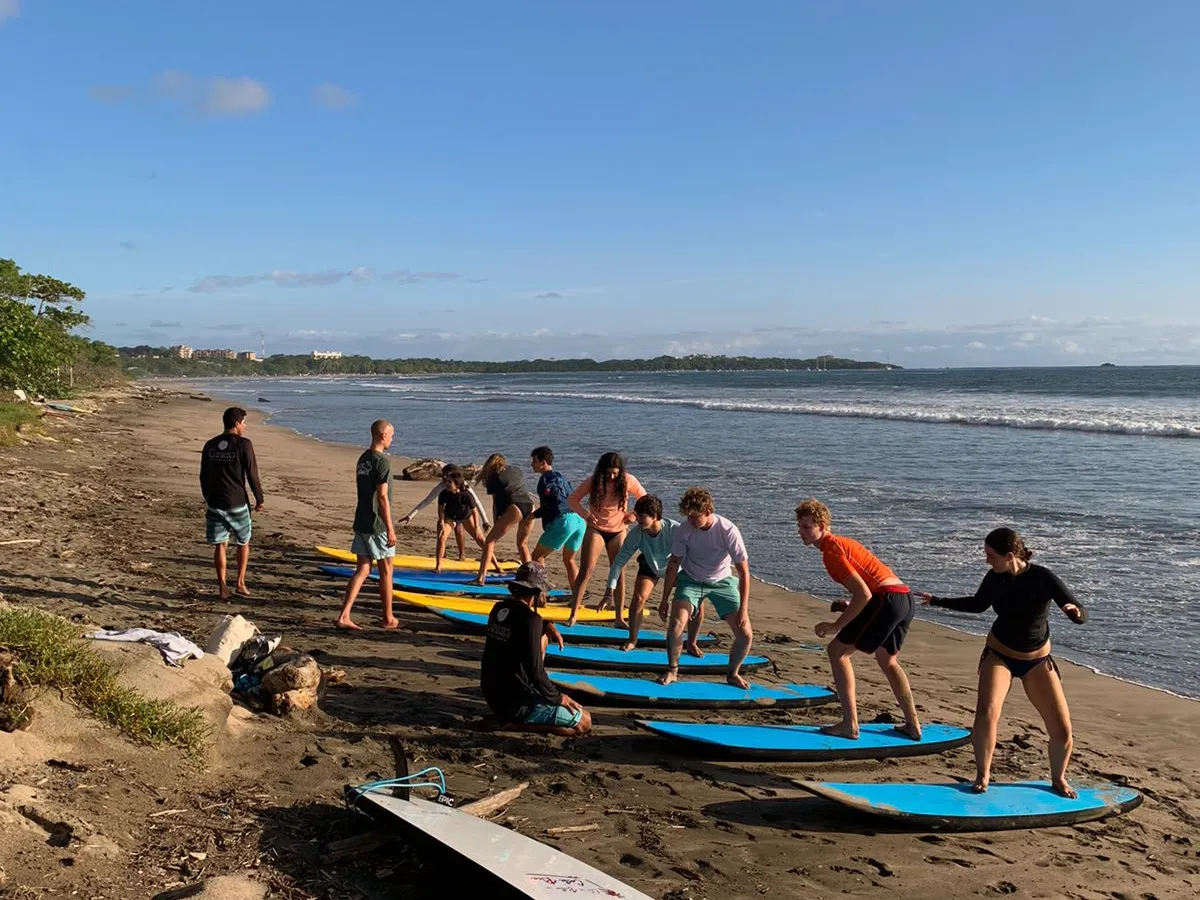 A group taking a beginner surf lesson with boards on a Pacific beach in Costa Rica