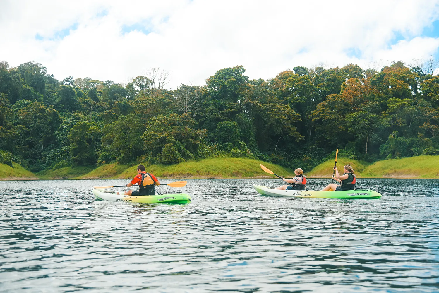 People kayaking on a calm lagoon backed by rainforest in Costa Rica