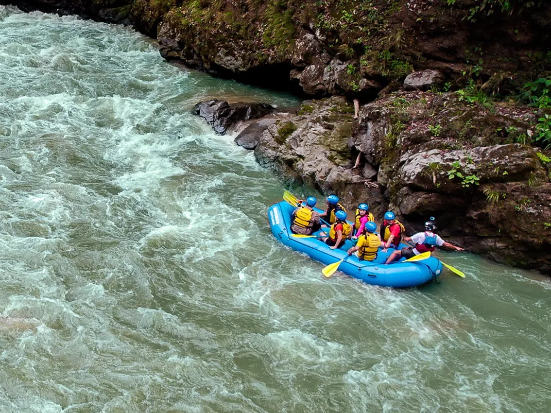 A group whitewater rafting through a rocky river canyon in Costa Rica