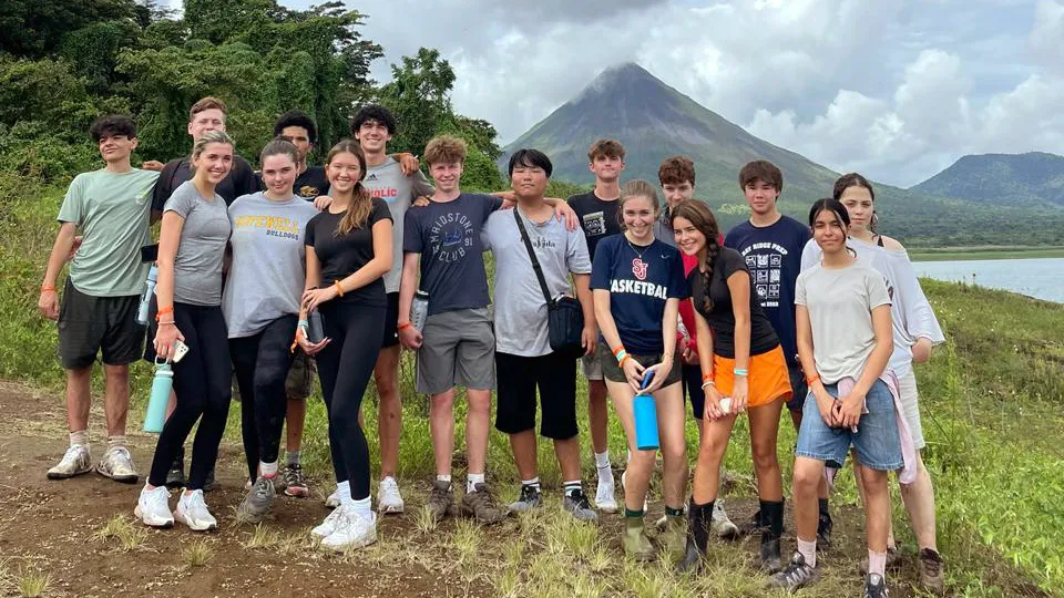 A group of students posing with Arenal Volcano and its lake behind them in Costa Rica