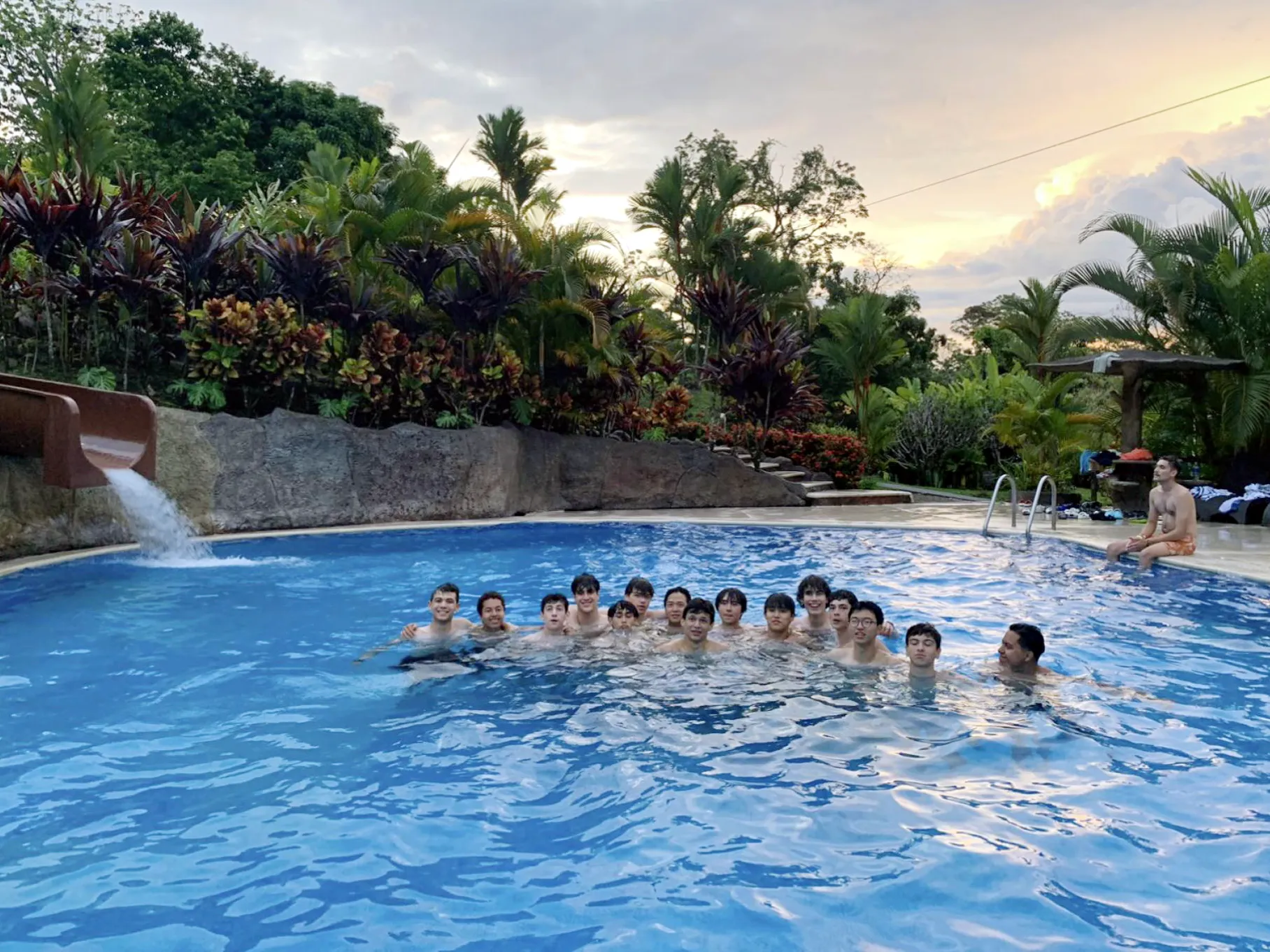 A group of students cooling off in a pool with a water slide in Costa Rica