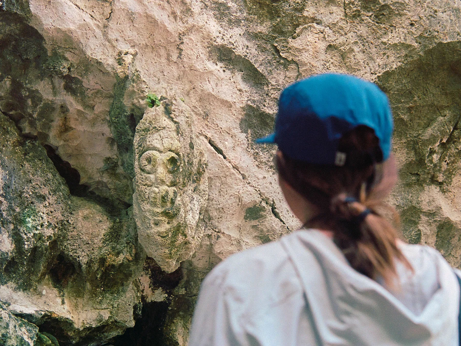 A traveler examining a carved Taíno petroglyph on a cave wall in the Dominican Republic