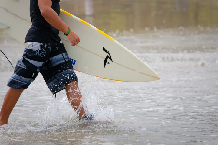 A surfer carrying a board through the waves in Costa Rica