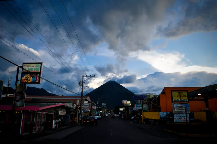 Arenal Volcano shrouded in clouds behind a small-town street in Costa Rica