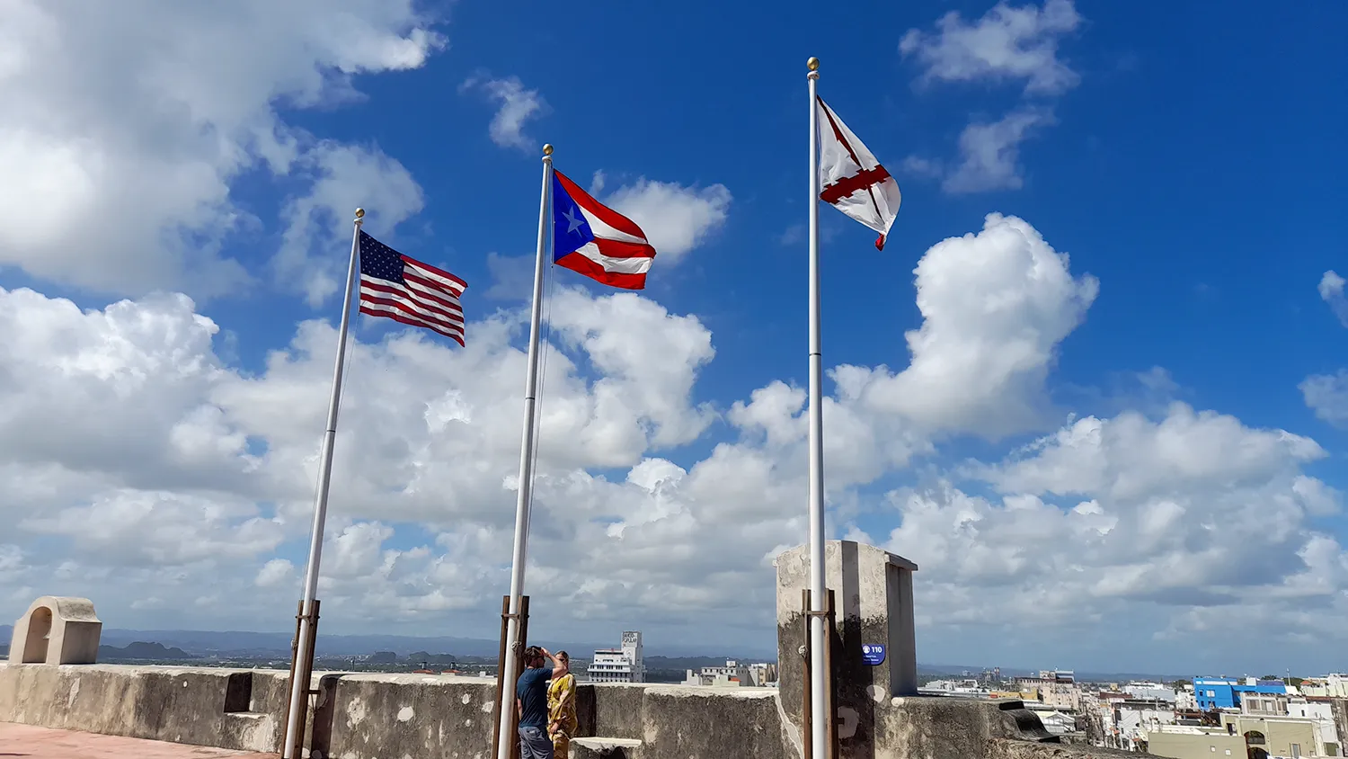 The U.S. and Puerto Rico flags flying against a blue, cloud-filled sky in Puerto Rico