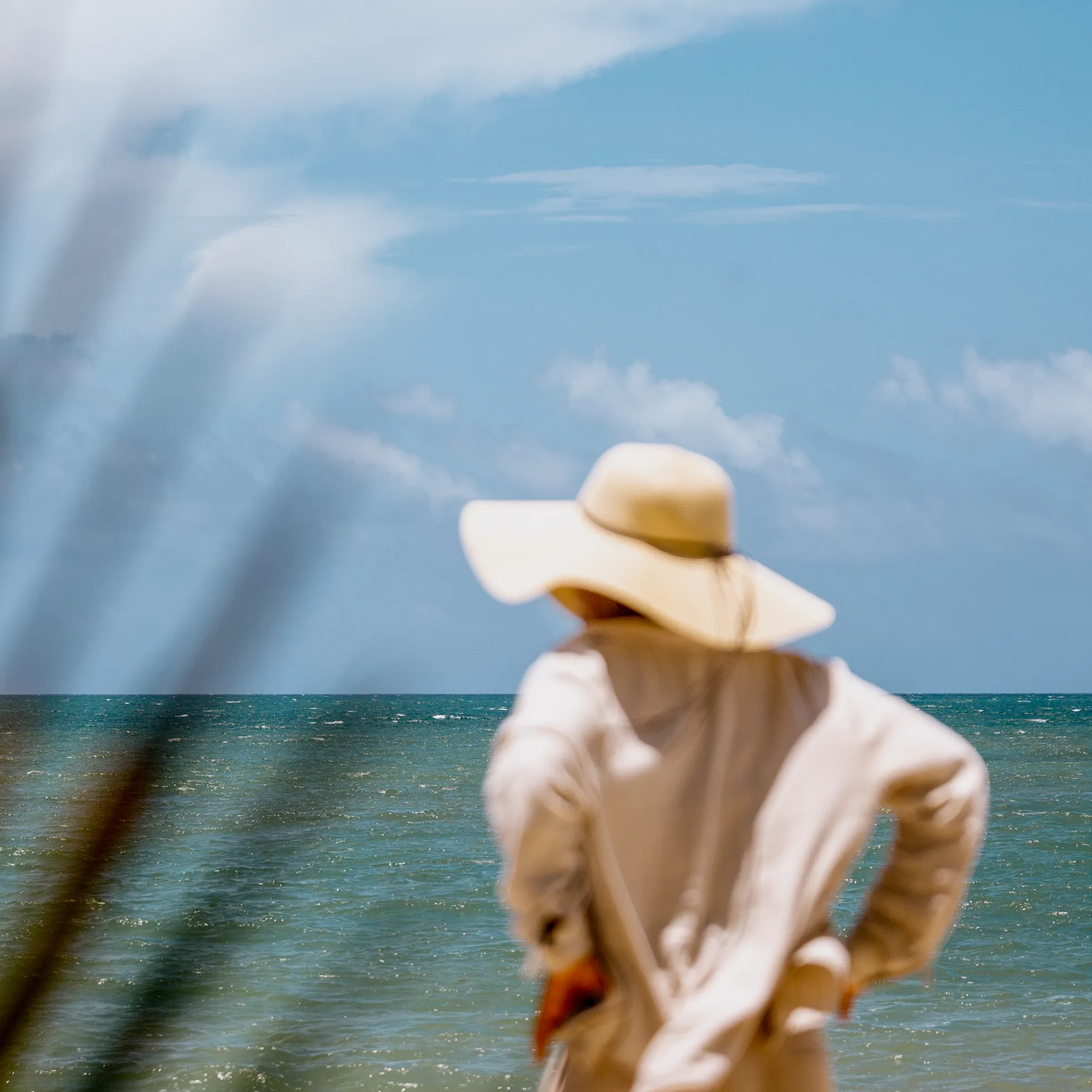 A person in a wide-brimmed straw hat looking out over the ocean in Puerto Rico