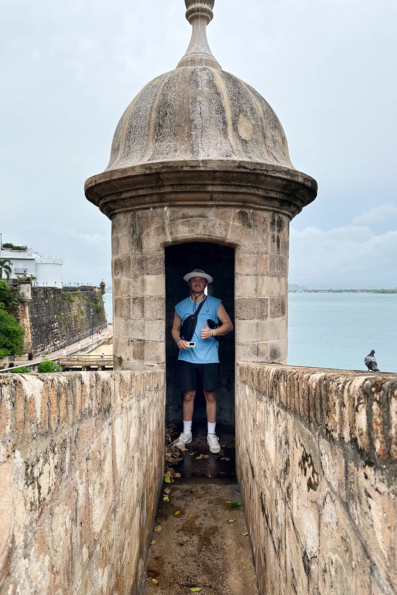 A person standing in the stone sentry box of a historic fort overlooking the sea in San Juan, Puerto Rico