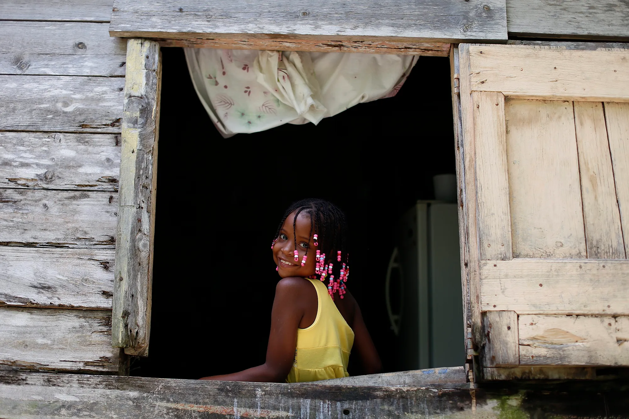A child standing in the doorway of a wooden house in the Dominican Republic