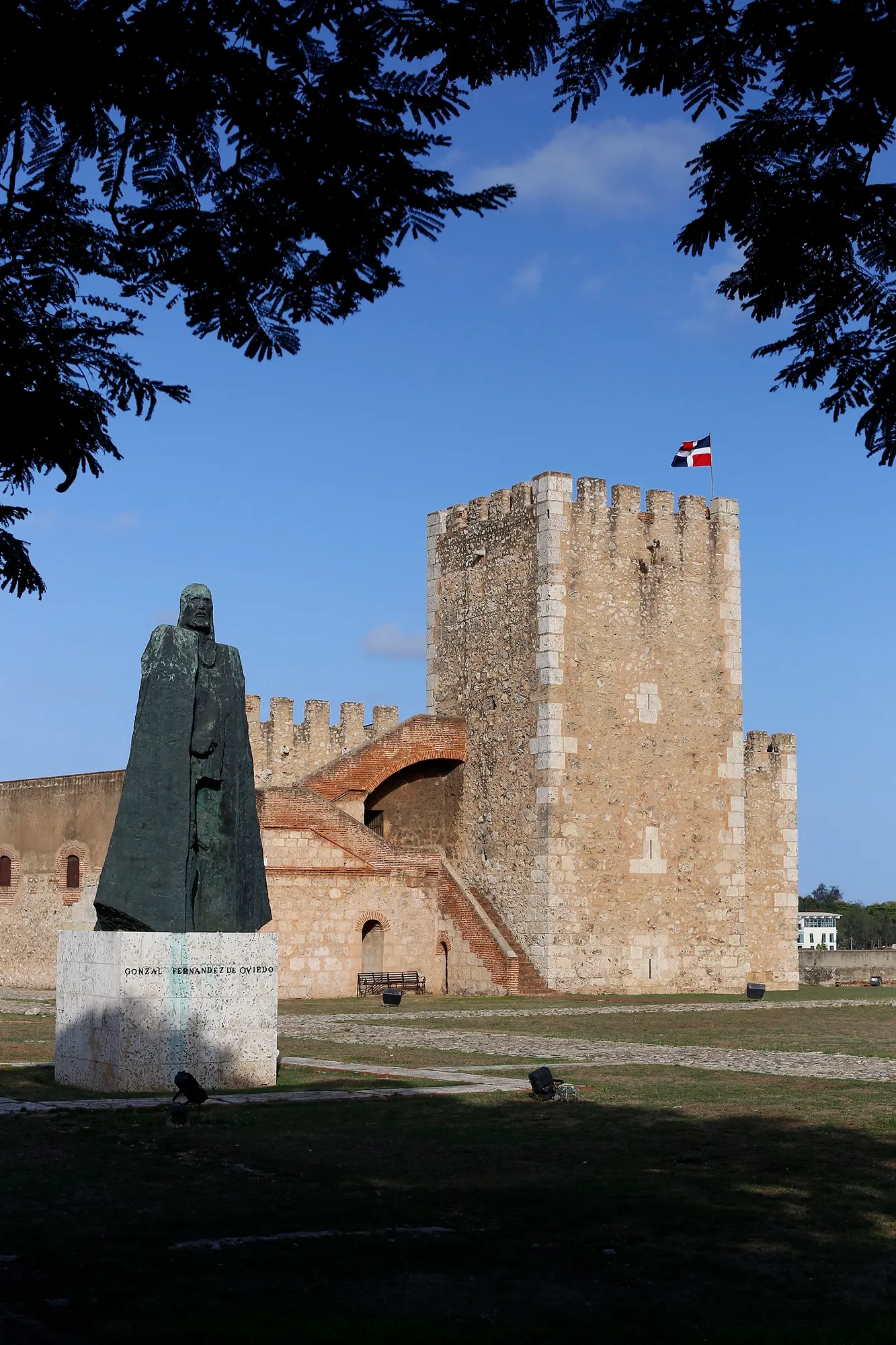 A statue beside a historic stone fortress tower in Santo Domingo, Dominican Republic