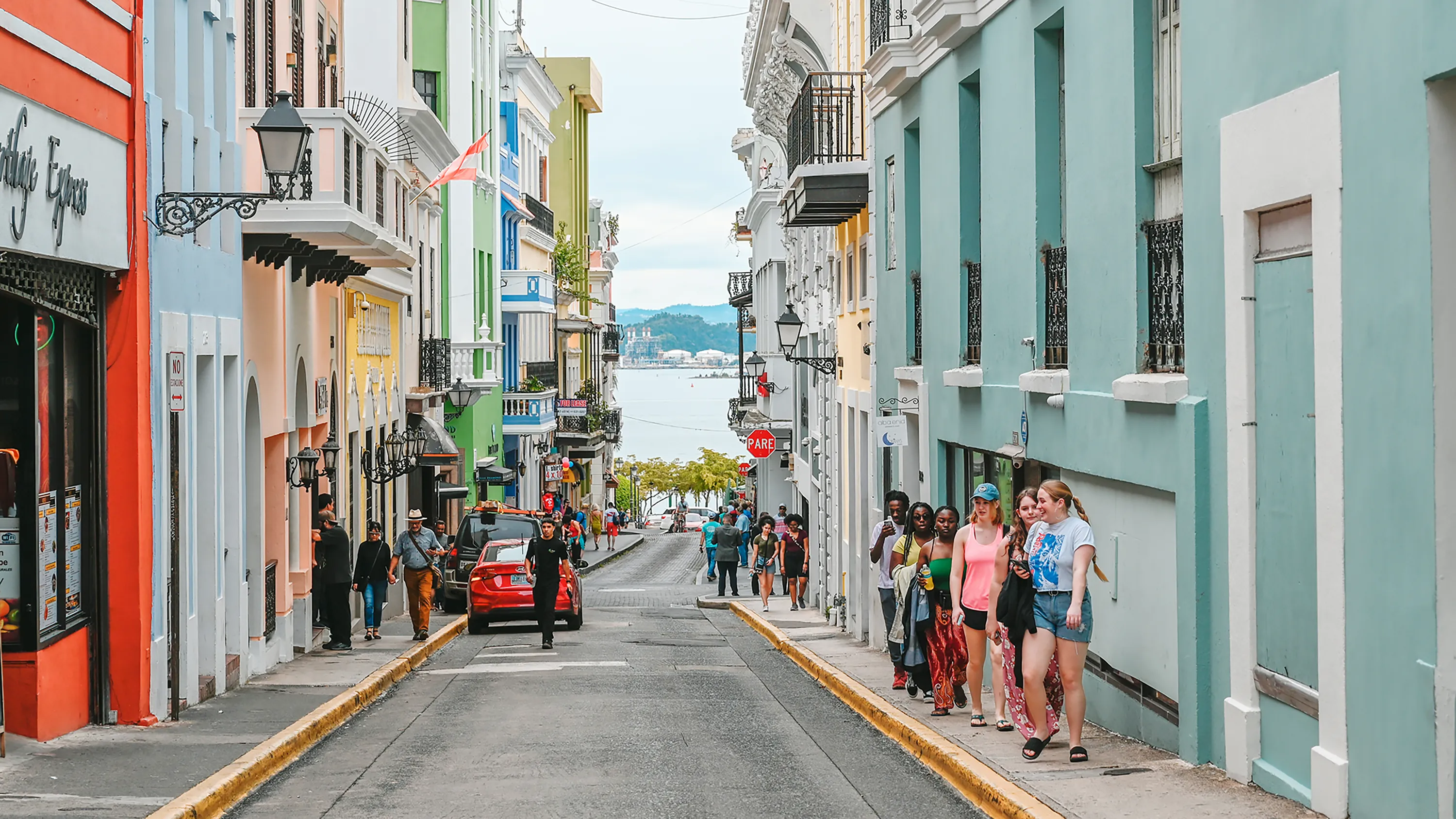 A narrow street of pastel buildings sloping toward the sea in Old San Juan, Puerto Rico