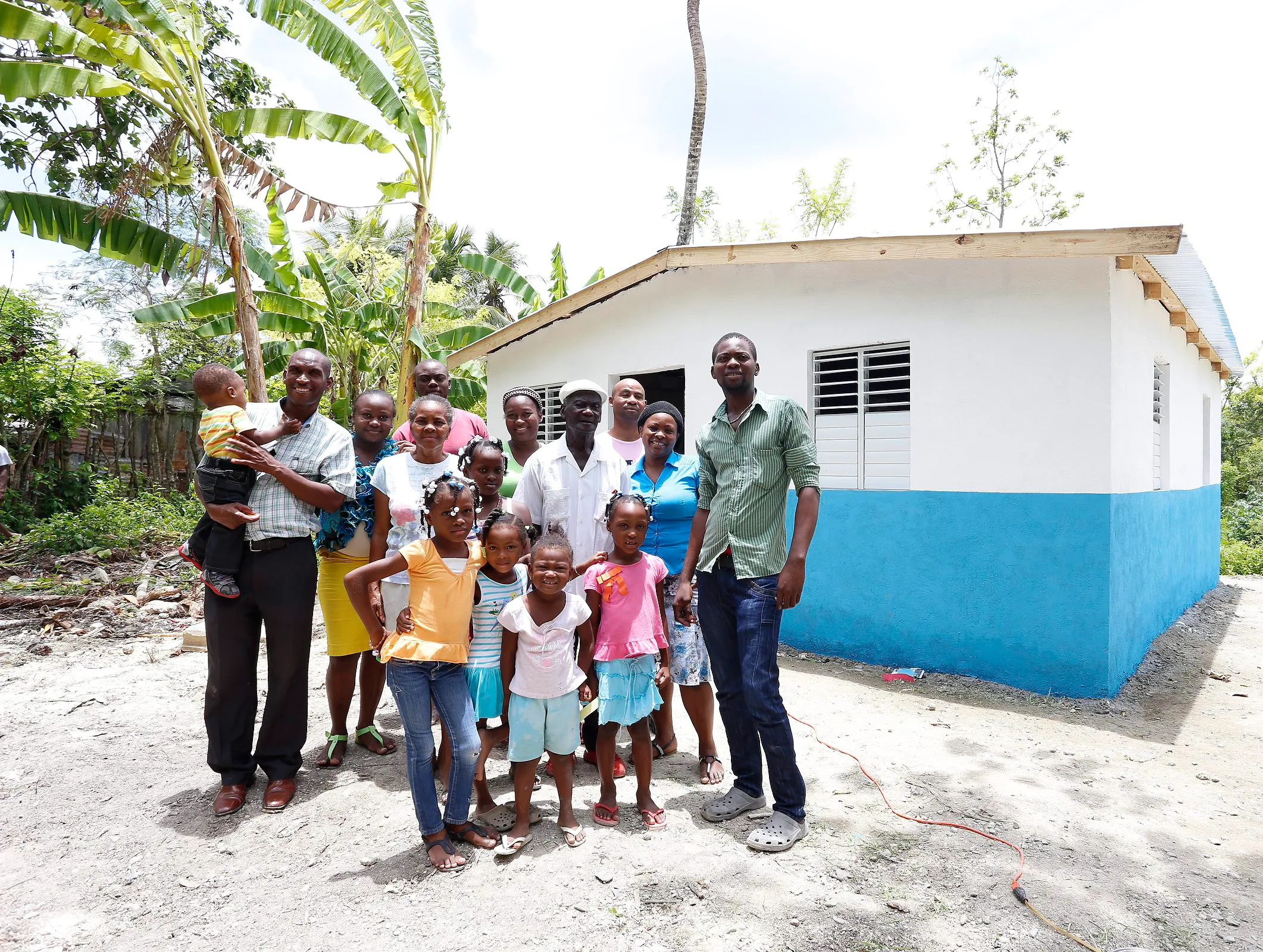 A large family posing in front of a blue-and-white house in the Dominican Republic