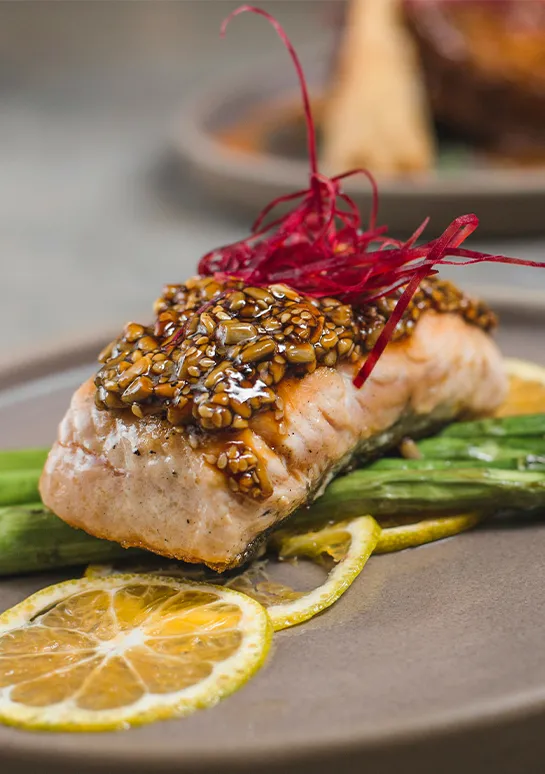 Glazed salmon with a seed crust over asparagus and lemon slices